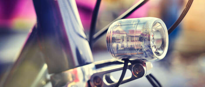 Nahaufnahme eines silbernen Fahrradlichtes. Darin spiegelt sich das Rathaus von Schwetzingen