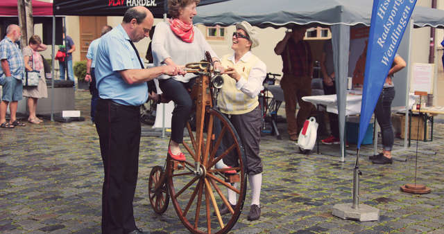 Eine Frau versucht auf einem historischen Rad zu fahren